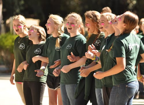 Counselors with linked arms sing a song