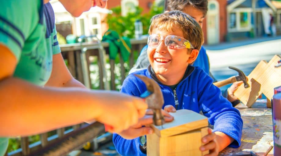 Young boy smiles while doing carpentry