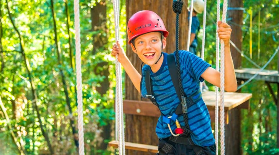 Smiling camper walks across ropes course