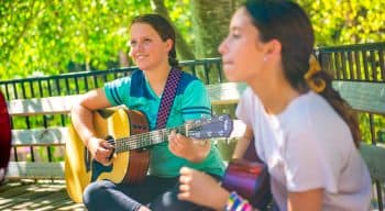 A girl smiling playing a guitar