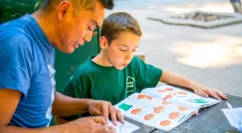 Staff member helps camper do origami