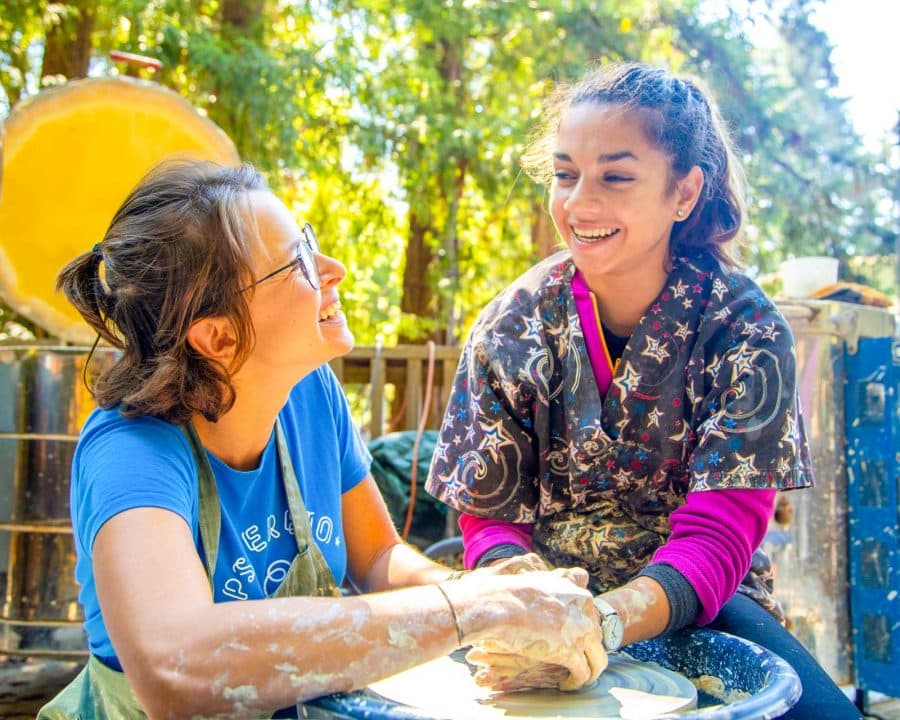 Staff member helps girl make ceramics at summer camp