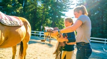 Girls getting ready to put a saddle on a horse