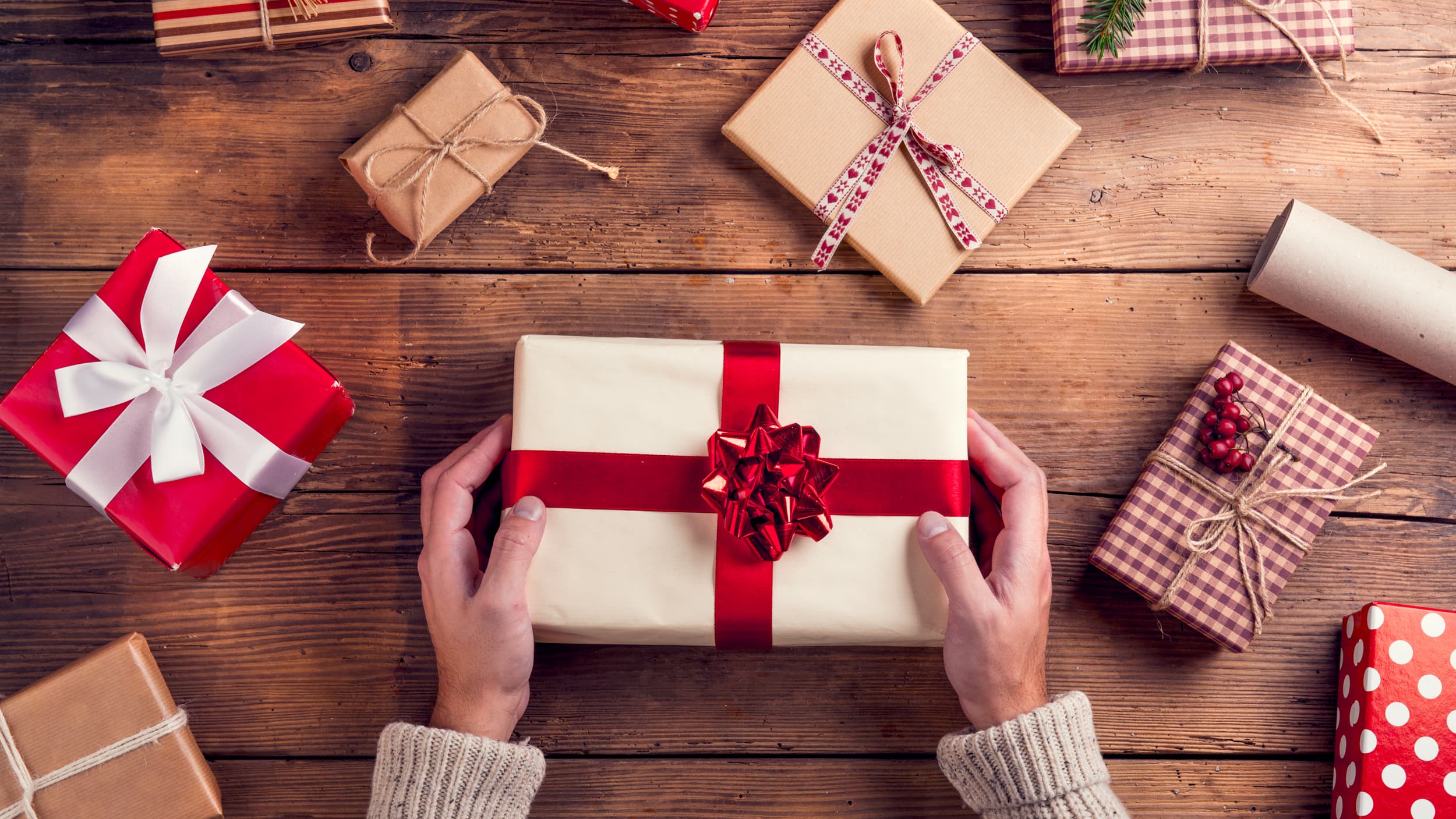 a woman holding a wrapped present on a table