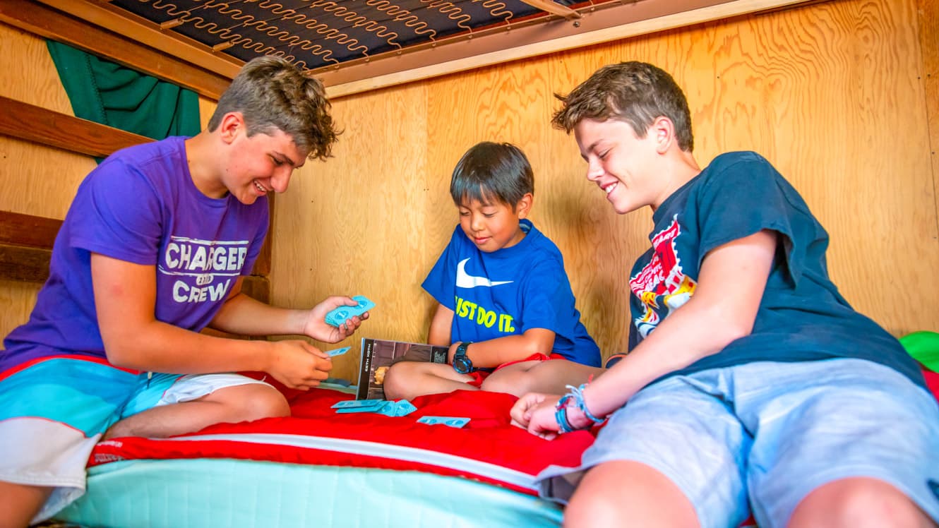 Boys play cards on camp cabin bunk