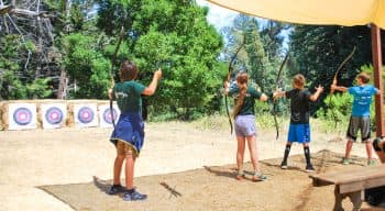 Four campers aiming bow and arrows at targets