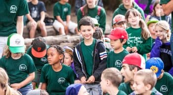 A camper zippering his jacket up in the middle of a group of campers