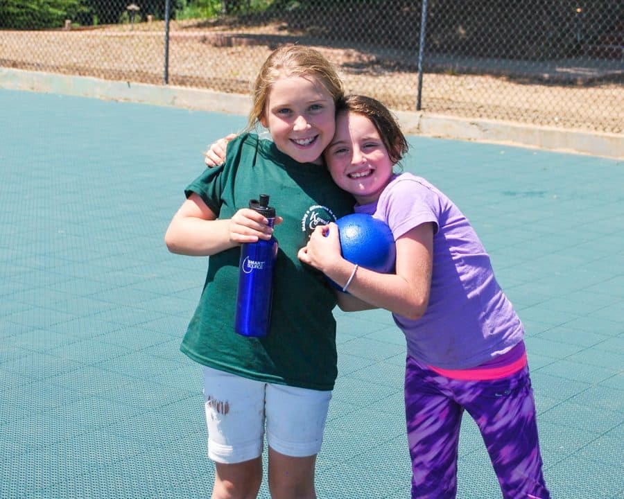 Two smiling day campers hug