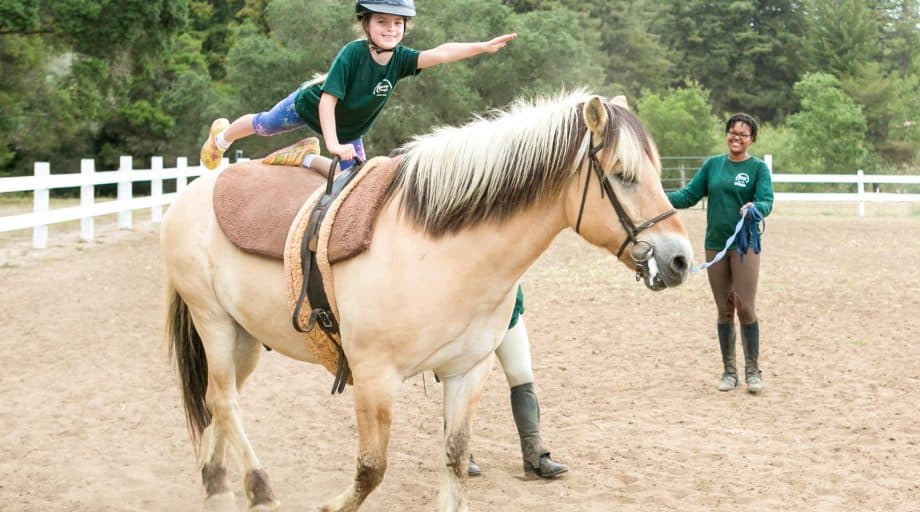 A girl doing a yoga pose on a horse