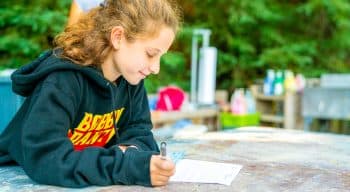 A girl writing a letter with a sweatshirt on