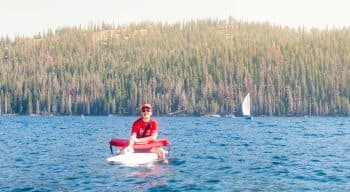 Lifeguard sits on surfboard on Huntington Lake