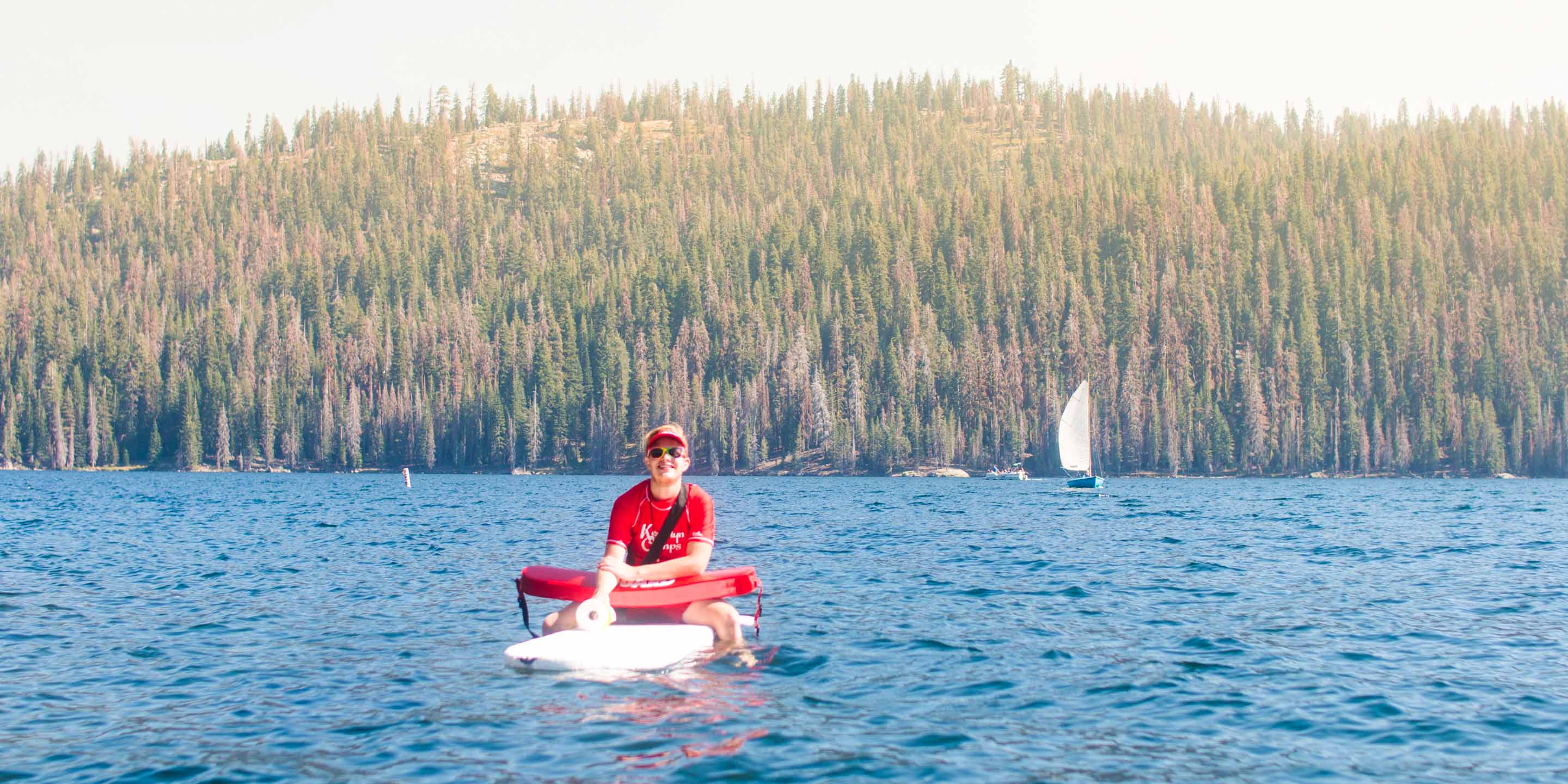 Lifeguard sits on surfboard on Huntington Lake