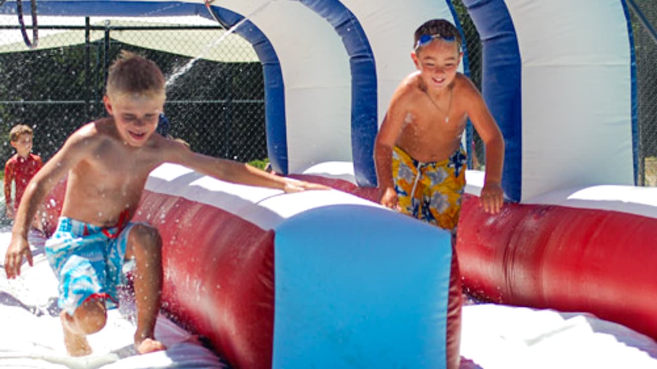 Boys running through inflatable waterslide