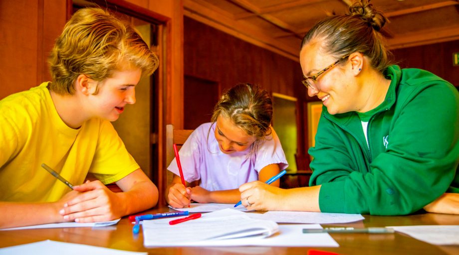 Two counselors helping a girl write