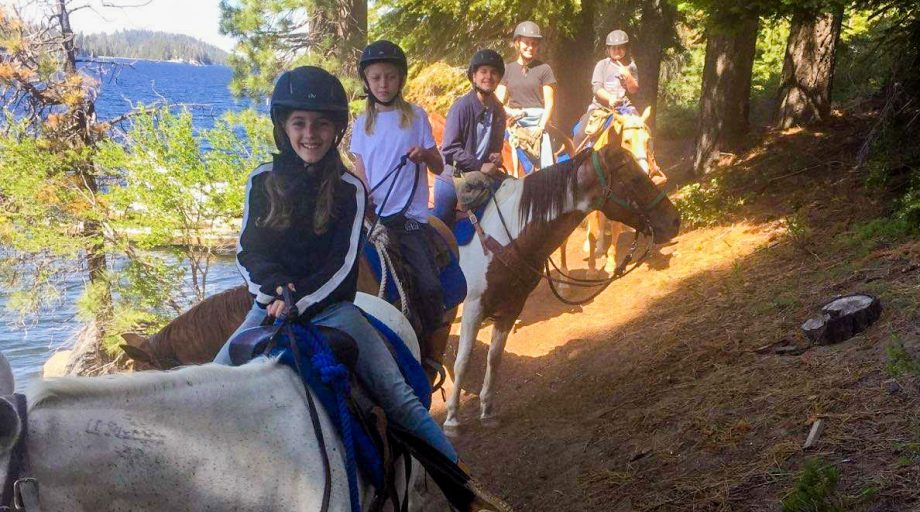 A group of campers on a trail with horses
