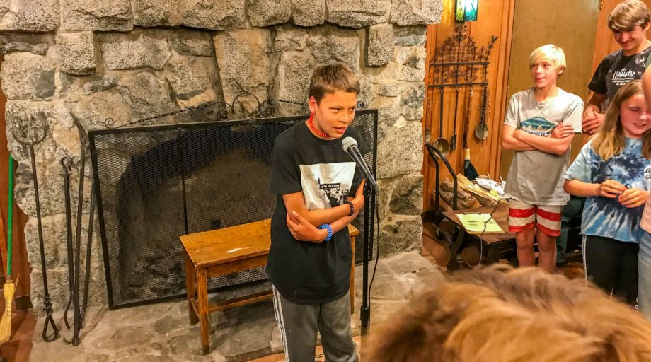 A boy speaking into a microphone in a lobby